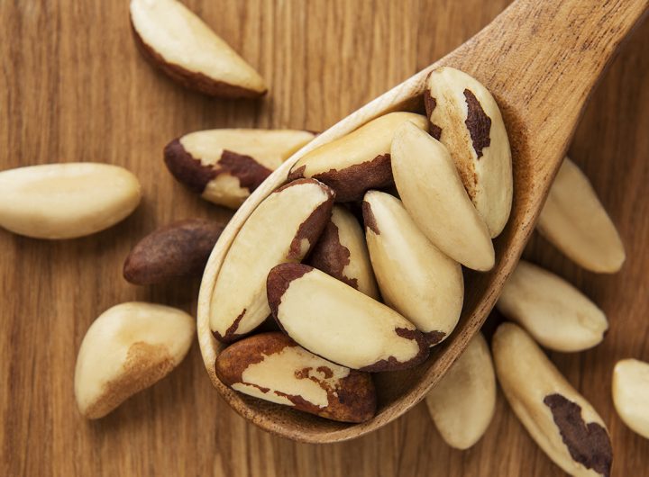 Spoon with Brazil nuts on wooden table