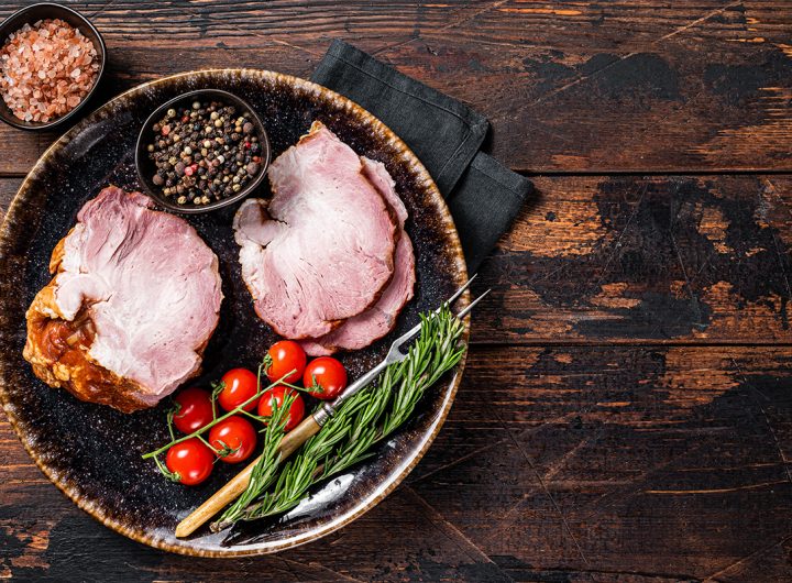 Smoked pork meat - gammon with herbs on rustic plate. Wooden background. Top view. Copy space.