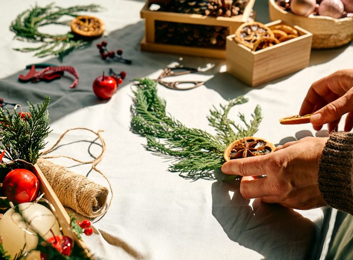 Woman making Christmas arrangement with fir branches and dried oranges. Female hands creating Christmas craft handmade decor. New year celebration. Winter holidays.