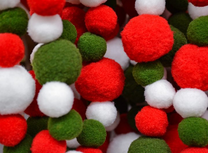 Bright garland of fluffy pompoms white, green and red as a festive background. Selective focus.