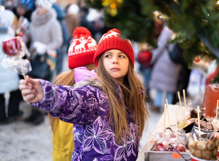 Cute girl with brother on Christmas market. Funny happy kid taking gift and sweets. Holidays, christmas, childhood and people concept. High quality photo